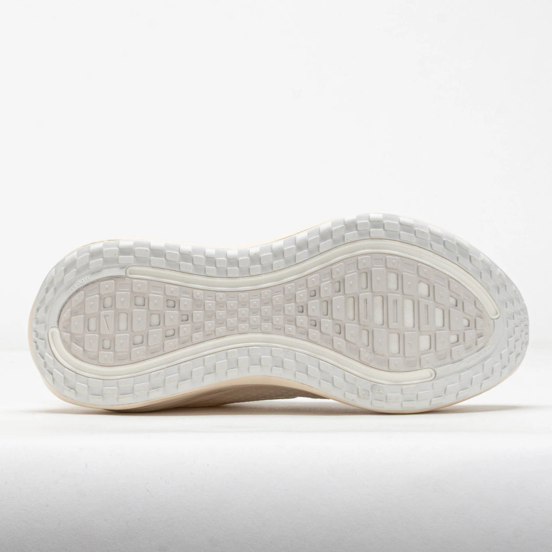 The outsole of a white athletic shoe, showing a textured tread pattern and a flexible white midsole, photographed against a clean white background.