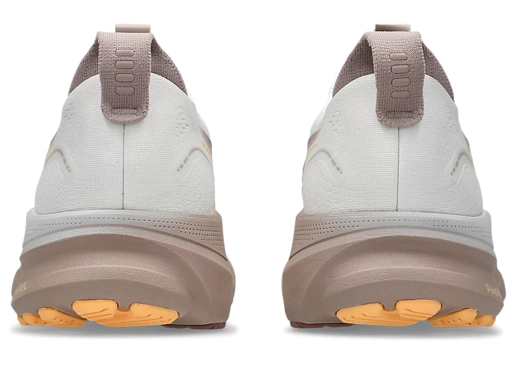 A pair of Gel-Kayano 32 running shoes shown from the rear, featuring a light gray and taupe upper with a thick taupe midsole and bright orange outsole accents.