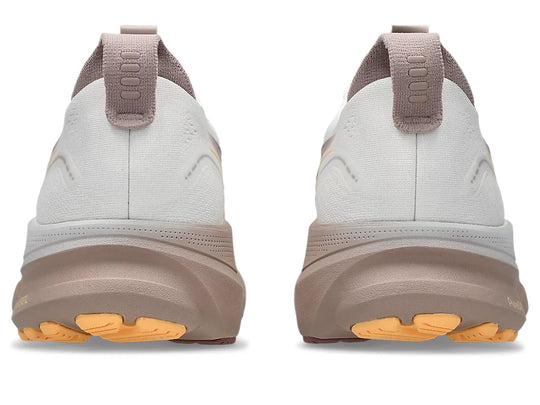 A pair of Gel-Kayano 32 running shoes shown from the rear, featuring a light gray and taupe upper with a thick taupe midsole and bright orange outsole accents.