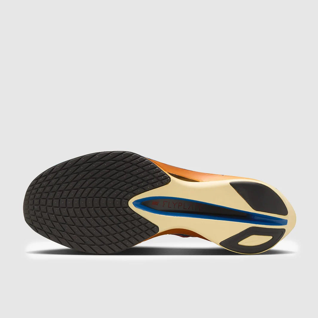 Close-up of a shoe sole with black tread pattern and gold and blue accents on a light gray background