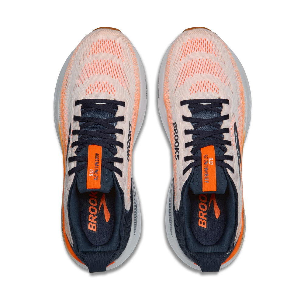 A pair of Brooks Men's Adrenaline GTS 25 running shoes shown from a top-down view on a solid white background. The shoes feature a light peach-pink mesh upper, navy blue laces and collar, and bright orange accents on the tongue, heel, and midsole.