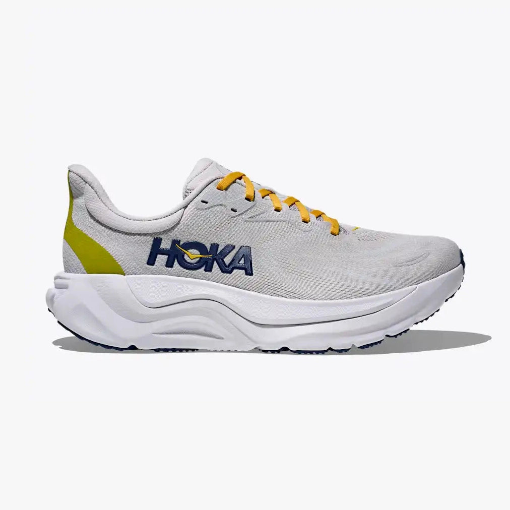 A Hoka Arahi 8 – Men's running shoe in light gray and white with yellow accents, featuring a white midsole and yellow laces, shown from a side profile on a light gray background.