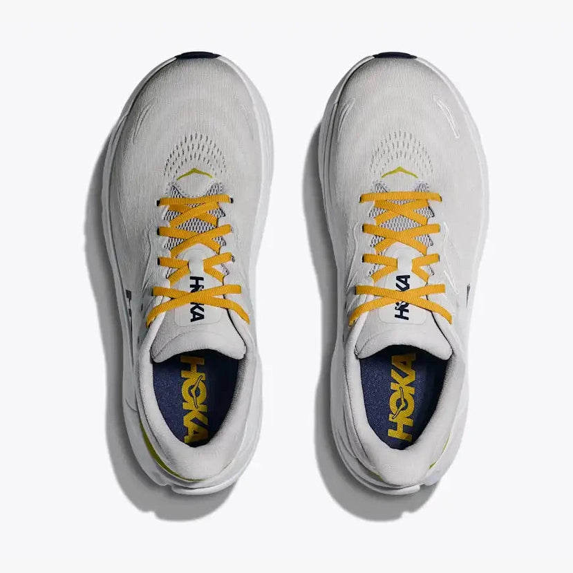 A pair of white Hoka Arahi 8 – Men's  running shoes shown from a top-down view on a light gray background. The shoes feature bright yellow laces, a yellow HOKA logo on the insole, and a dark navy blue interior lining.
