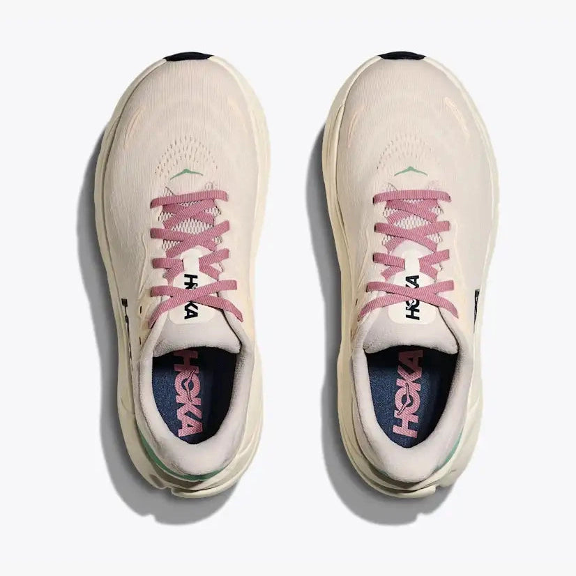 A pair of Hoka Arahi 8 – Women's running shoes shown from a top-down view on a light gray background. The shoes are primarily off-white with dusty pink laces and lining, black accents on the toe caps and tongue, and a dark navy interior.