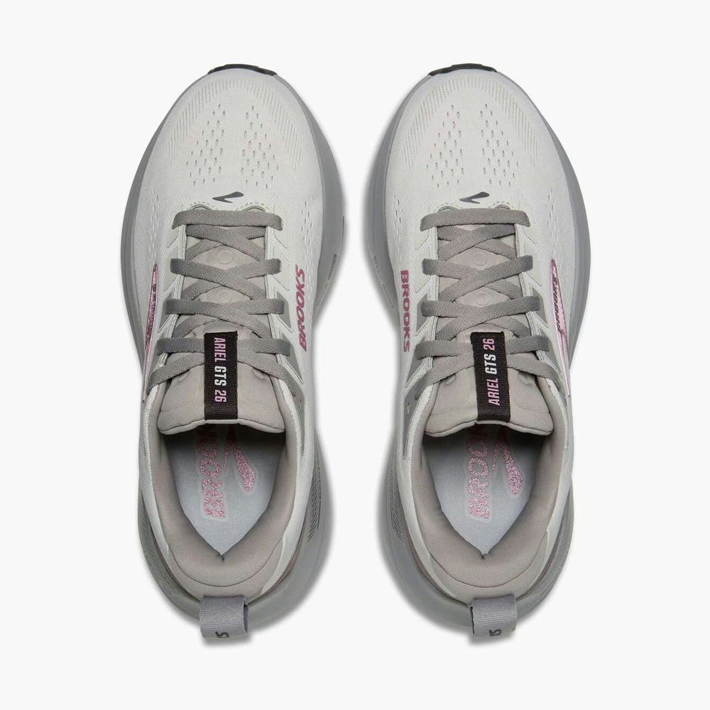 A pair of Brooks Ariel Gts 26 – Women's running shoes shown from a top-down view on a light gray background. The shoes are primarily off-white and gray with pink branding accents and black details on the tongue labels.