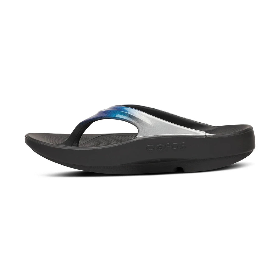 A single Oofos OOLALA sandal shown in a side profile view against a plain white background. The sandal features a black sole and strap, with a metallic silver arch support band and a blue-to-purple gradient accent on top.