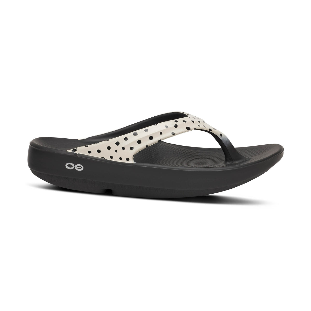 Black OOfos OOlala Limited sandal with a polka dot design on a white background