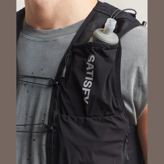 Person wearing a blackJustice Cordura 5L Hydration Vest with a water bottle, featuring the brand &