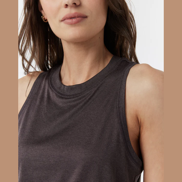 Close-up of a woman wearing a dark brown heather Vuori Energy Top – Women's sleeveless tank top, showing the crew neck and upper chest against a light neutral background.