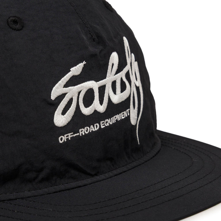 Close-up of a black Flitesilk 5 Panel Pinch Cap featuring a large white embroidered script logo and the text &