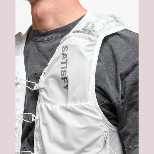 Close-up of a person wearing a white Justice Cordura 5L Hydration Vest brand hydration vest over a dark gray t-shirt, showing the white fabric, drawstring lacing, and vertical &