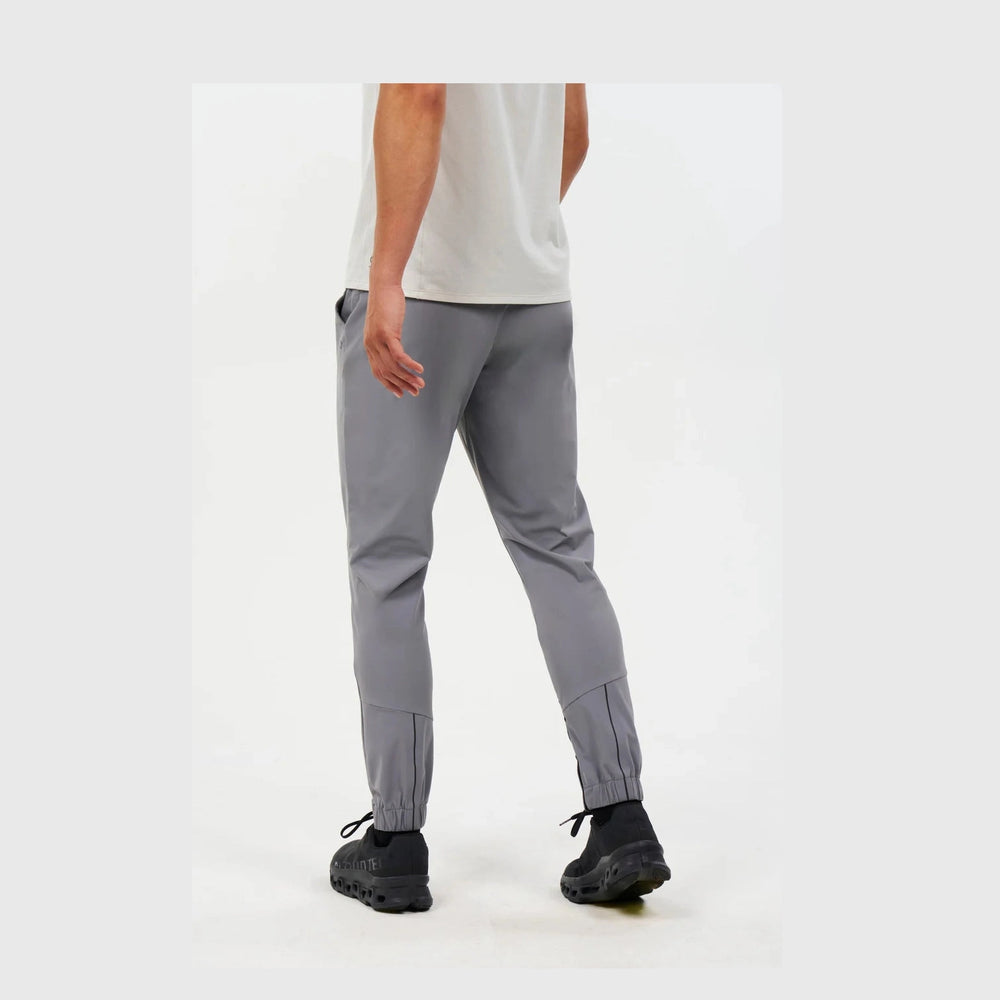 A person shown from the back wearing gray Alwrld Alrn Gran Sport Jogger – Men's with elastic cuffs, paired with a light gray sleeveless top and black sneakers, against a plain light background.