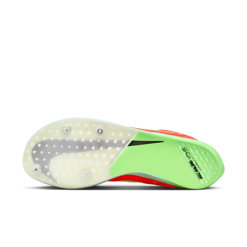 The outsole of a Nike track shoe, showing the translucent white plate, gray sticky pads, neon green heel, and red toe section on a white background.