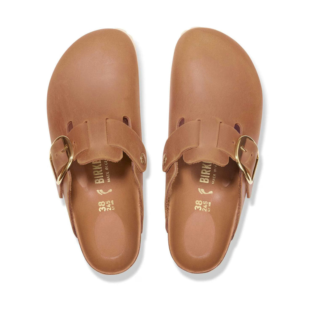 A pair of tan leather Birkenstock Boston Big Buckle, shown from a top-down view on a white background. The brand name 'BIRKENSTOCK' is visible on the insoles.