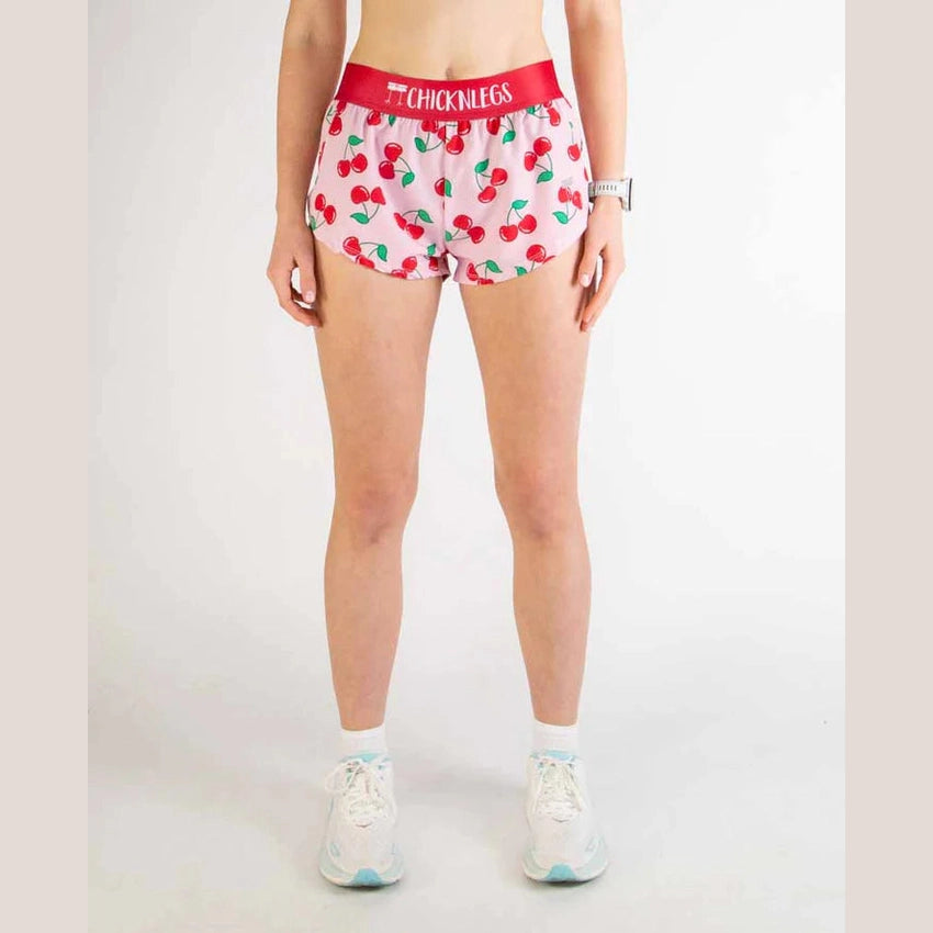 Person wearing cherry-patterned Chicknlegs 1.5" Split Shorts – Women's with a red waistband on a white background