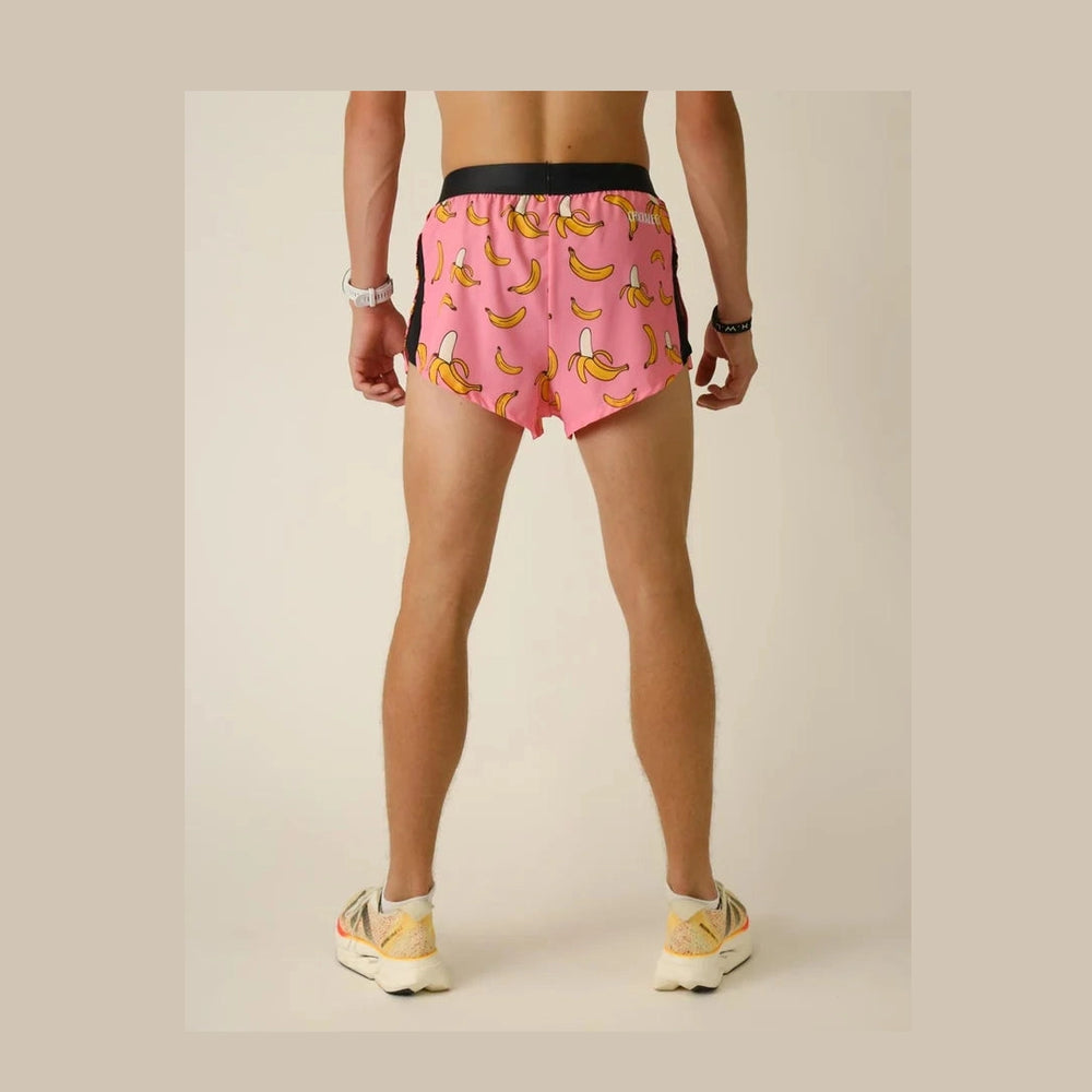 A person shown from the back wearing pink Chicknlegs 2" Split Shorts – Men's with a banana print, black waistband, and black side panels, standing against a plain light beige studio background.