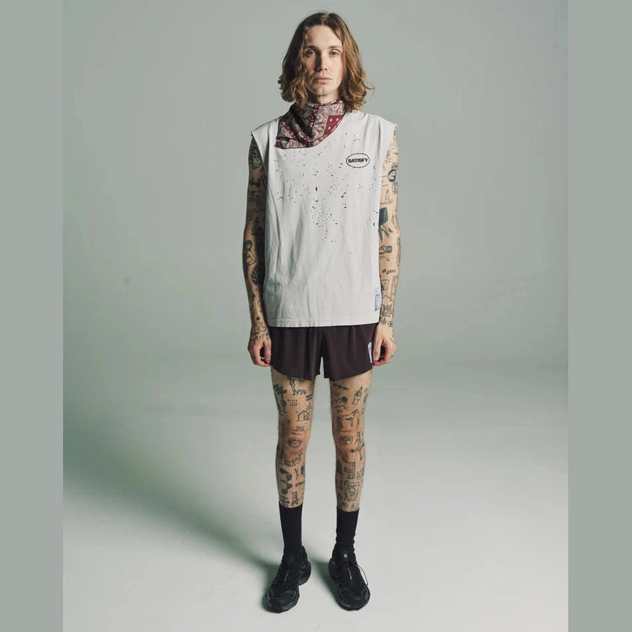 A model with tattoos stands against a light gray studio background wearing a sleeveless white vest with a small circular logo on the chest, a patterned bandana at the neck, Space-O Shorts--Men&