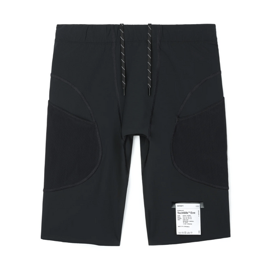Satisfy Evo Half Tight 9 inches in Black has unique high-rise silhouette, large side pockets, a drawstring waist, and a white size tag attached near the lower right hem, shown on a plain white background.