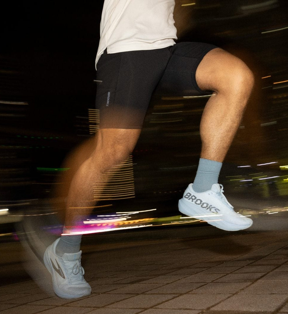 Person running on a city street at night with blurred lights