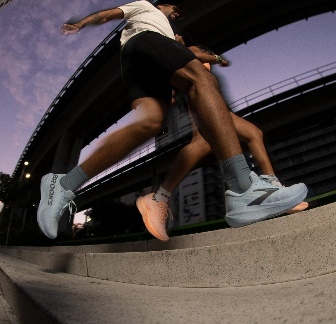 Two people running on a concrete ledge with a cityscape background
