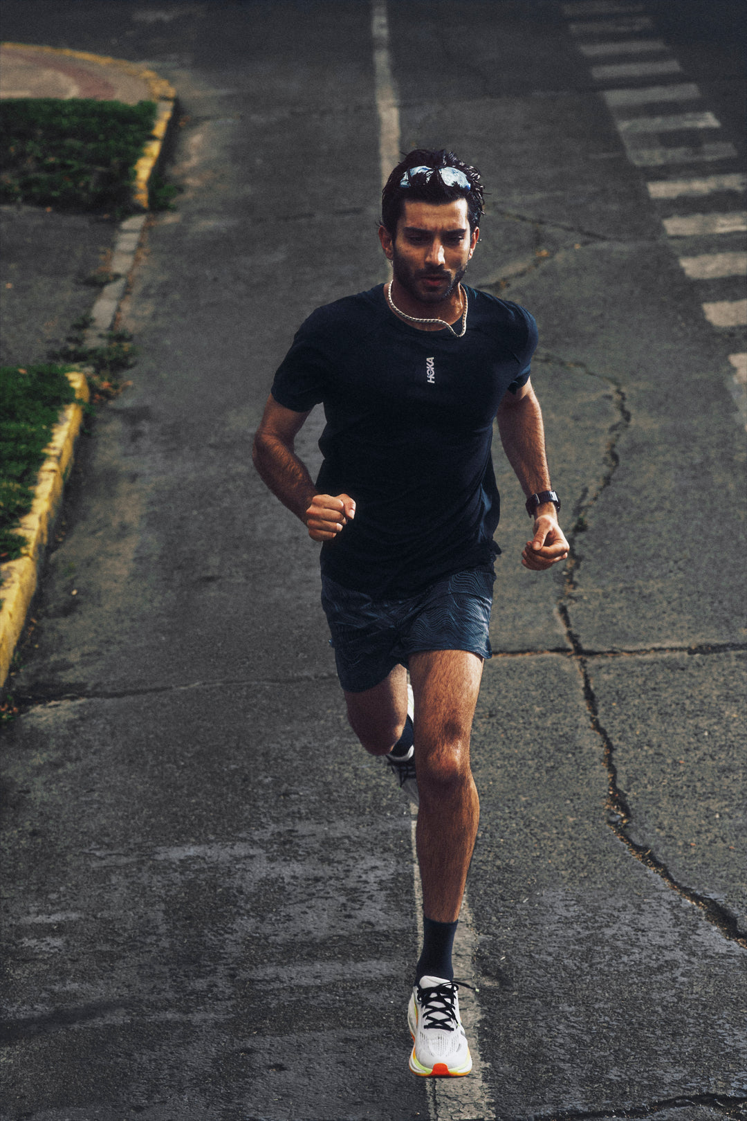 Man running on a road with a blurred background in a Hoka Clifton Pro shoe.