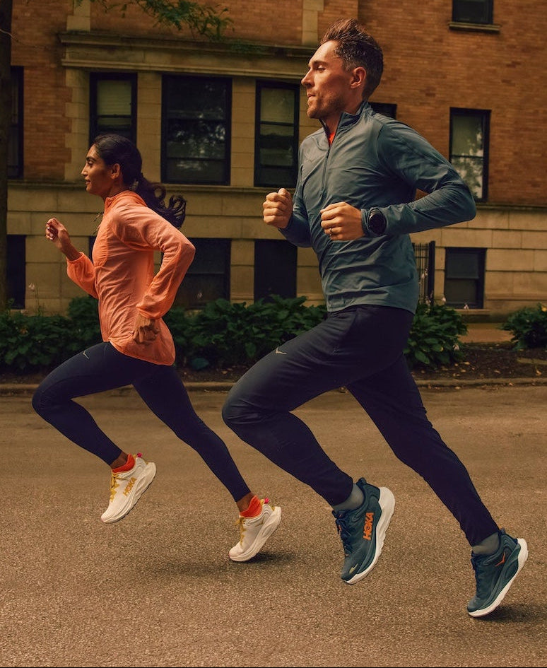 Two people running on a street with a building in the background