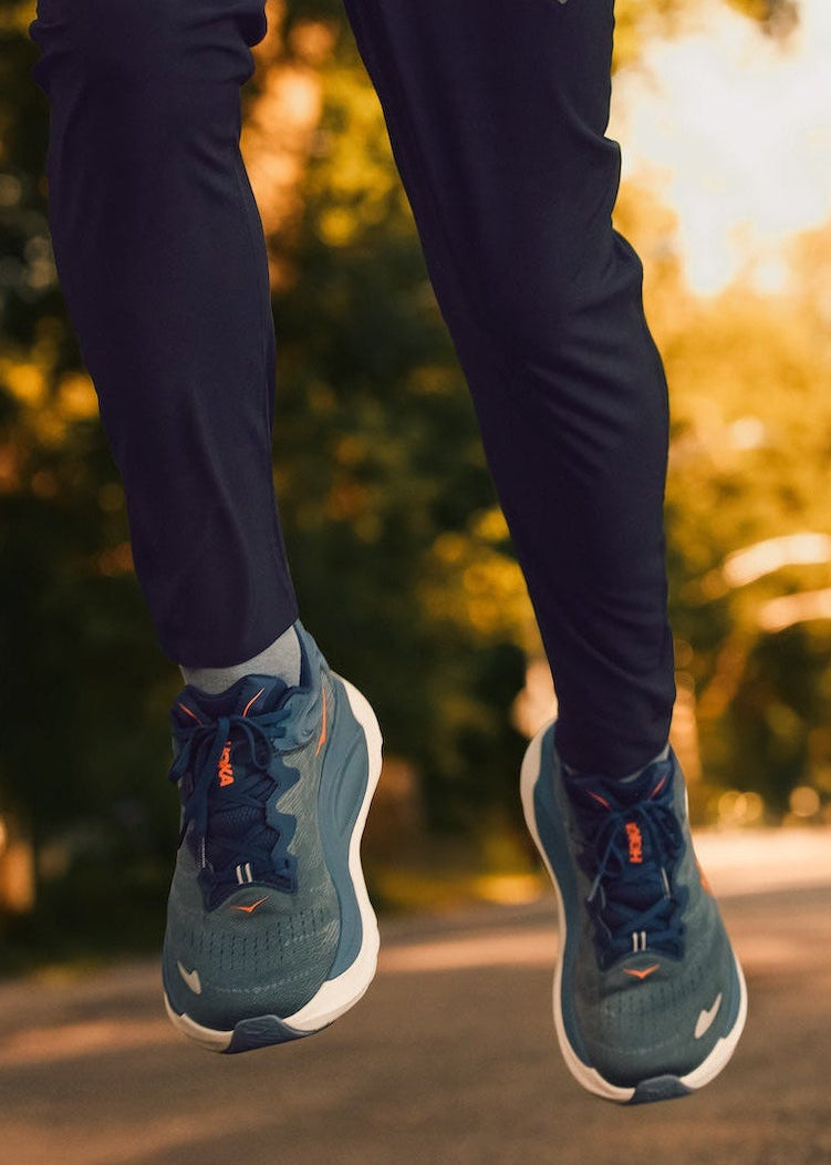 Man running in the Hoka Gaviota 6 sneaker on a path with trees in the background