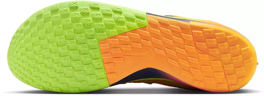 Close-up of the textured outsole of a Nike athletic shoe, showing a bright lime green section on the left and a vibrant orange section on the right, with a small dark Nike swoosh logo visible in the center.