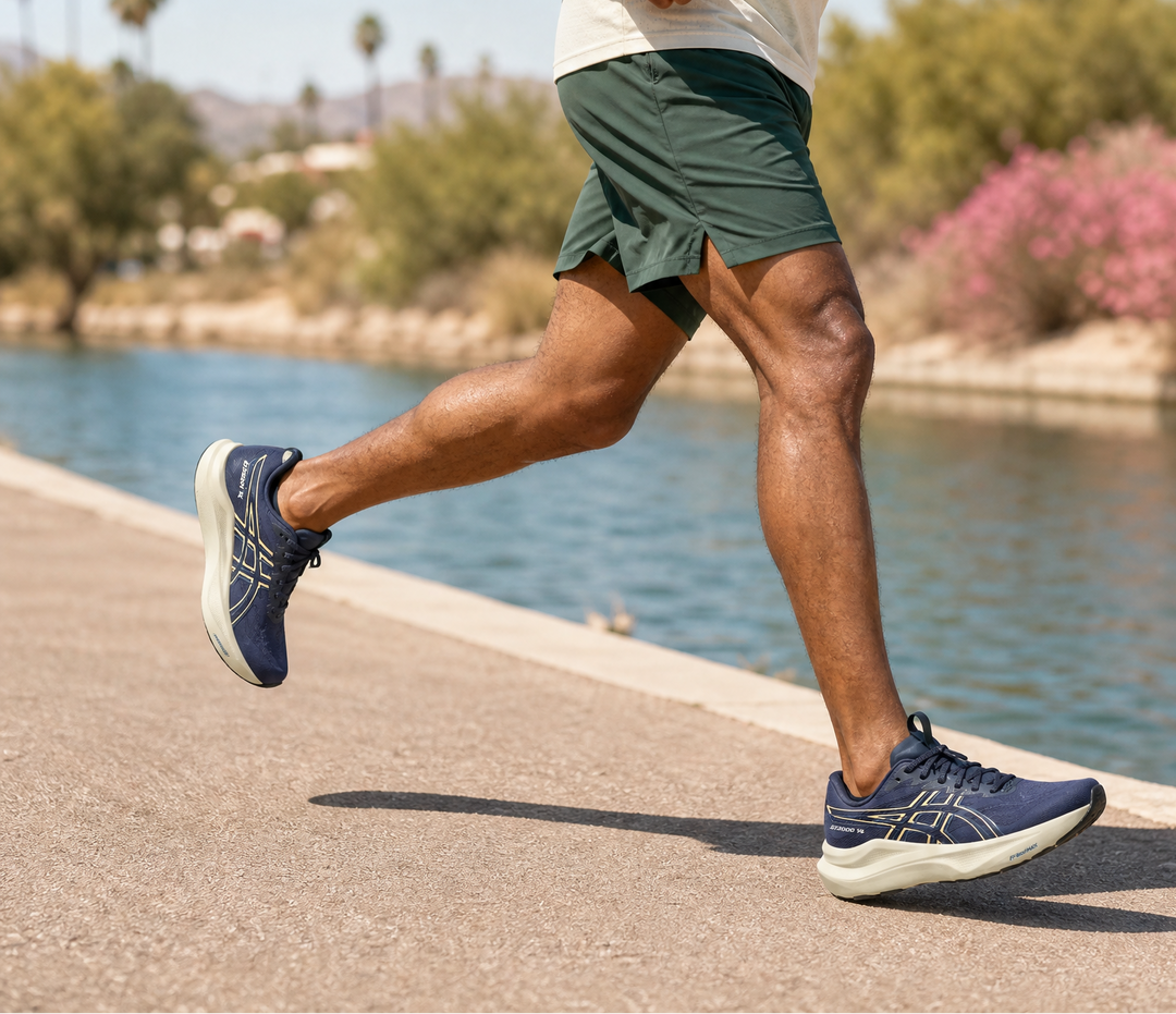 Man running on a path by a lake with trees and pink flowers in the background