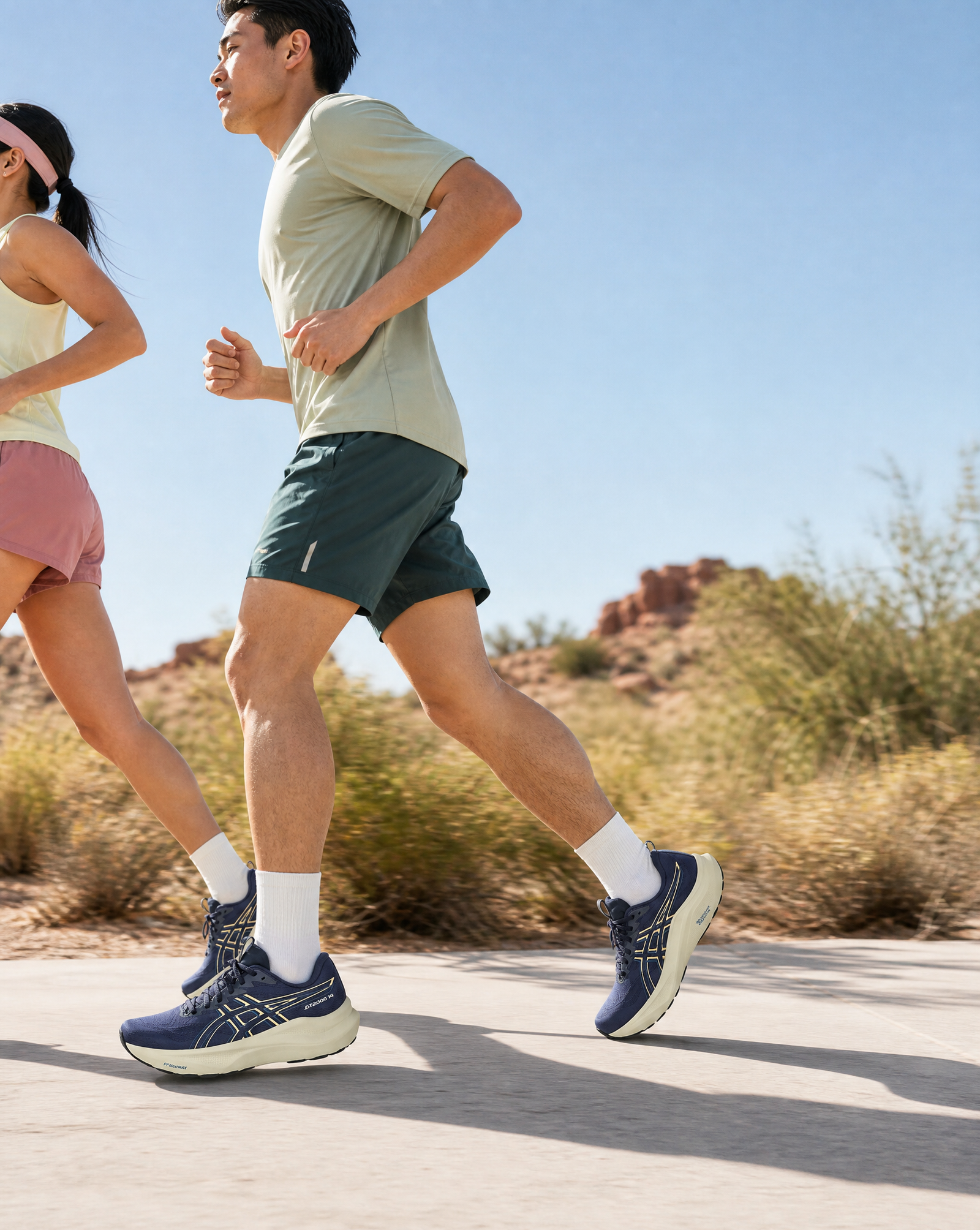 Two people running on a road with a desert landscape in the background