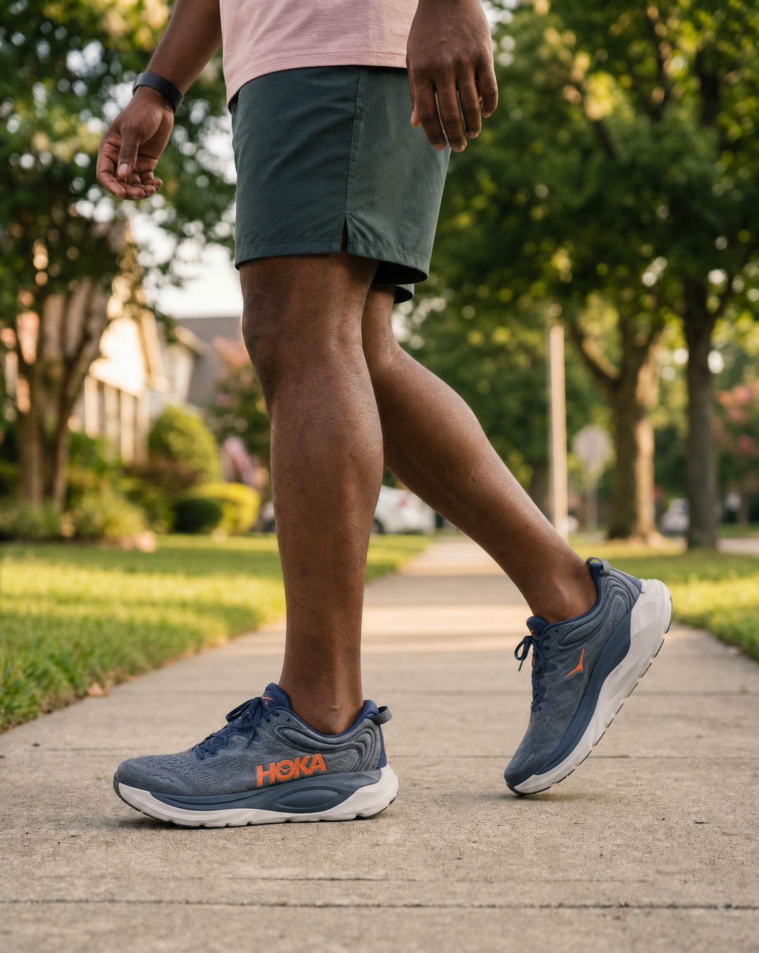 Person wearing blue Hoka Gaviota 6 running shoes on a sidewalk with greenery in the background