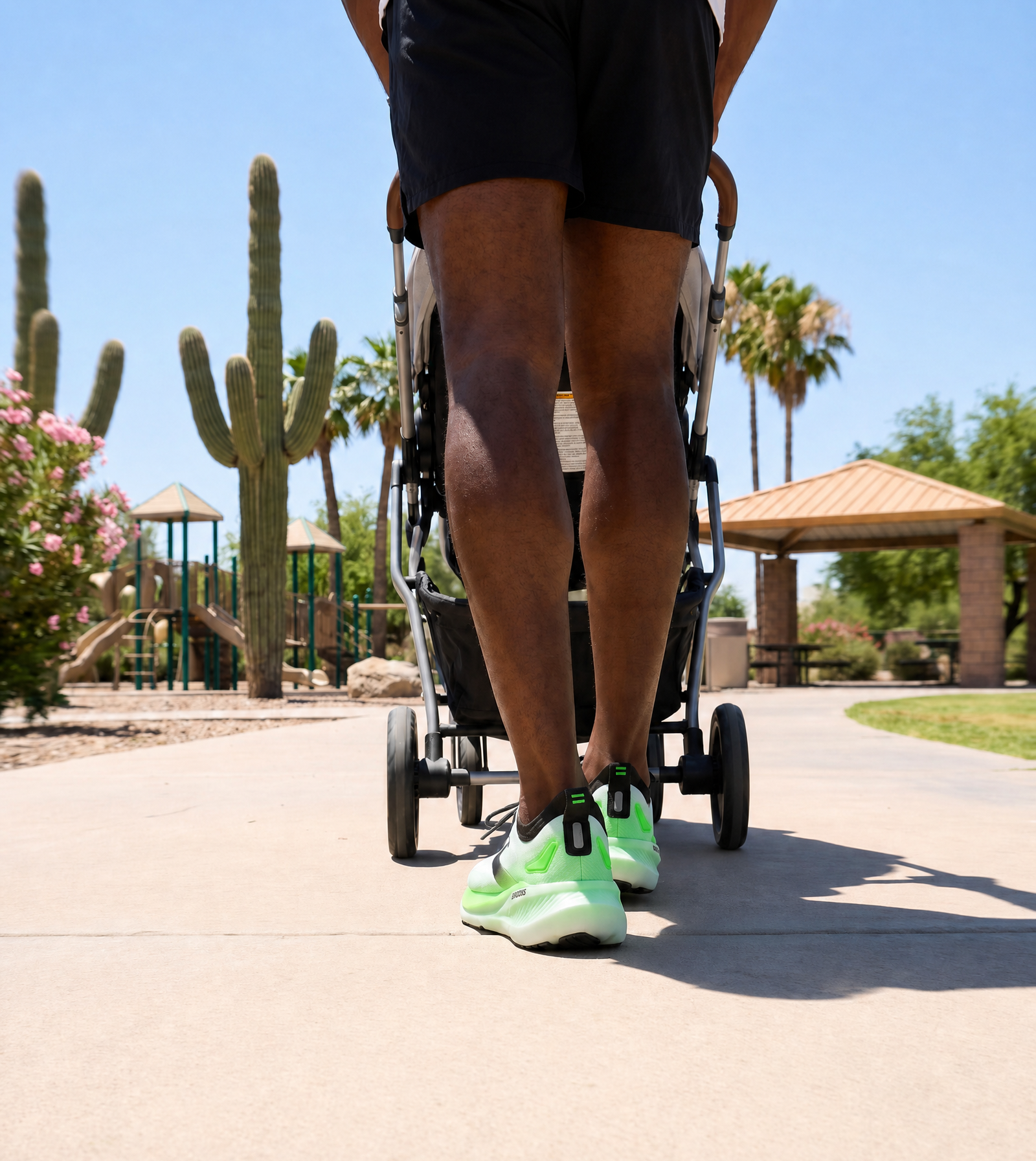 Person wearing the Mens Brooks Glycerin 23 pushing a stroller with cacti and a clear blue sky in the background