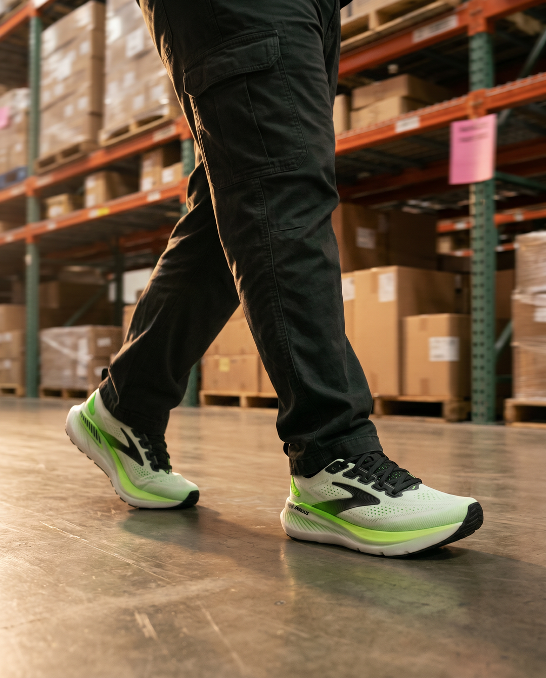 Person wearing white and green Brooks Glycerin GTS 23 athletic shoes in a warehouse setting