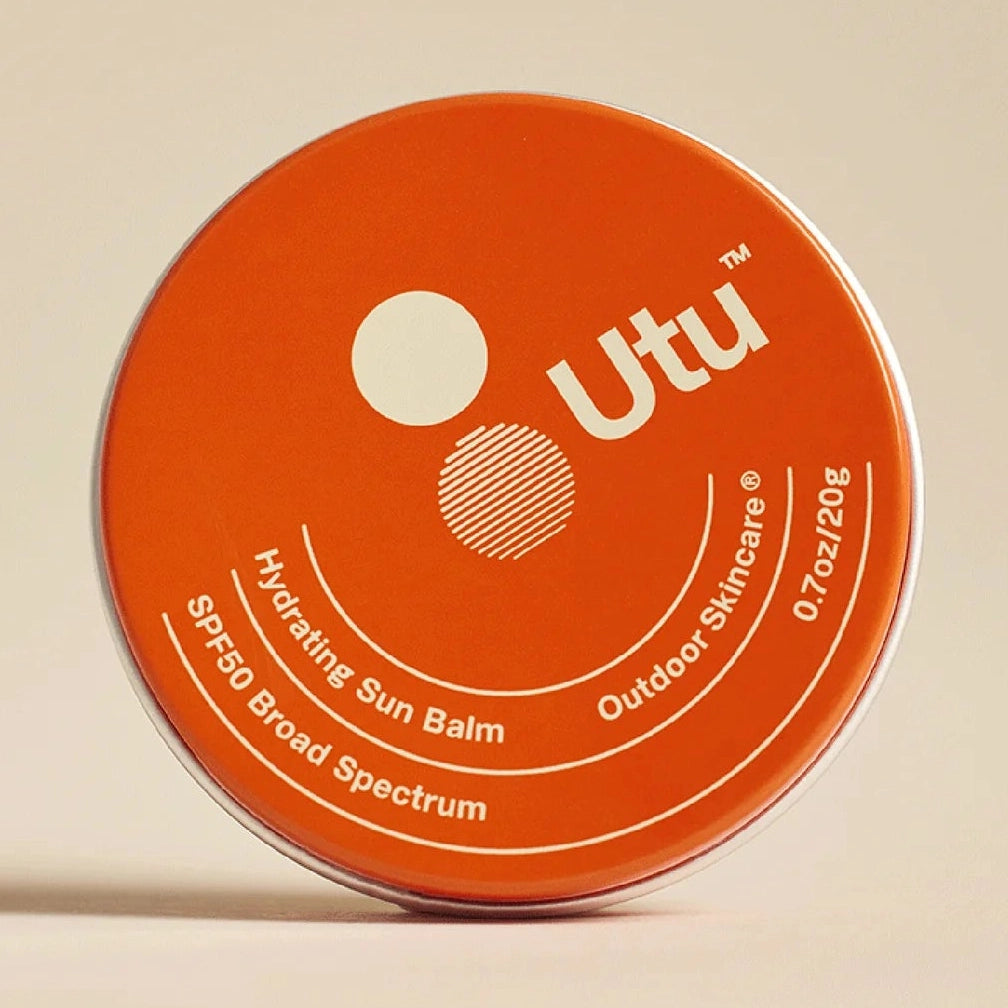 Orange container of UTU SPF 50 Hydrating Sun Balm on a beige background