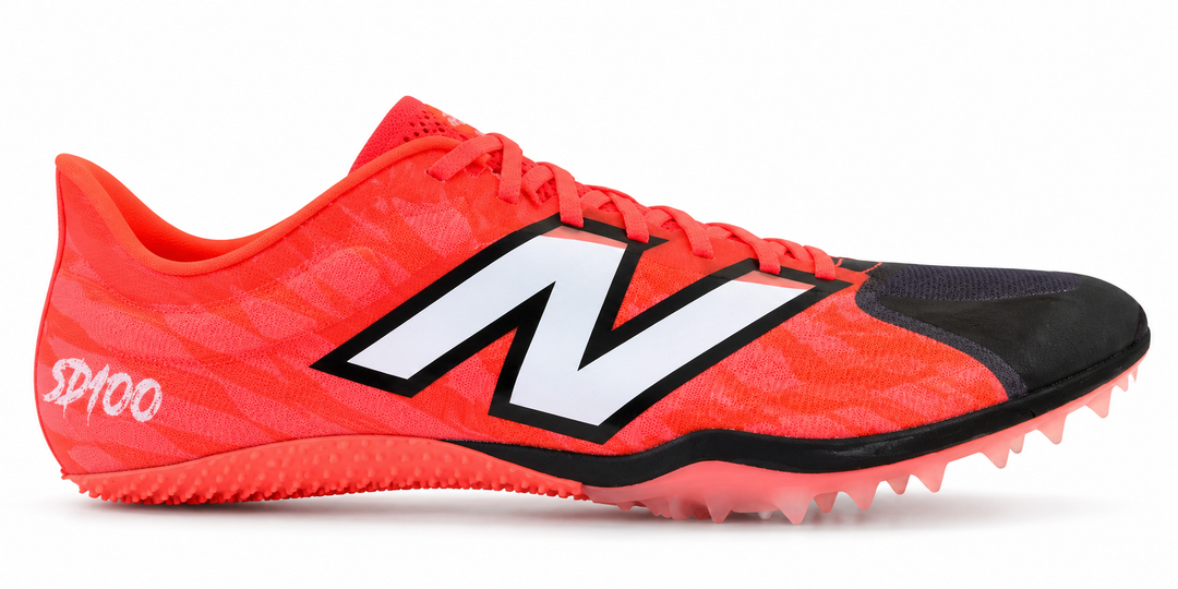 A New Balance Sd100 V5 – Men's track shoe in bright orange-red with a black toe cap, black and white 'N' logo, and spike sole, shown on a white background.