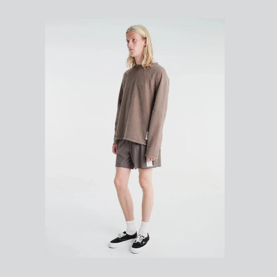 A model with long blonde hair stands in a studio wearing a textured taupe-brown Fuzz Fleece AD Long Tee--Men&
