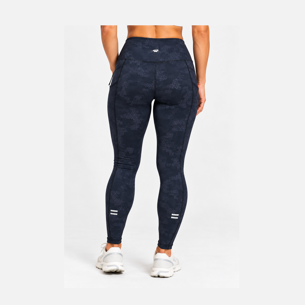 Rear view of a model wearing dark grey camouflage high-waisted 25" Running Tight – Women's with white sneakers, set against a plain light gray studio background.
