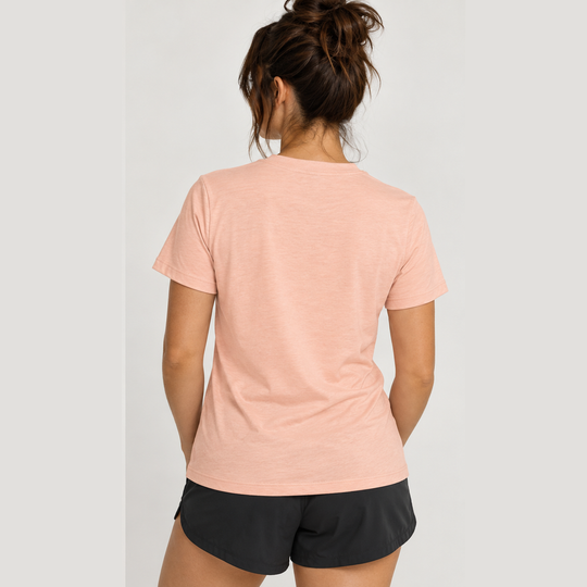 A woman shown from behind wearing a heathered light peach Classic Fit Tee – Women&