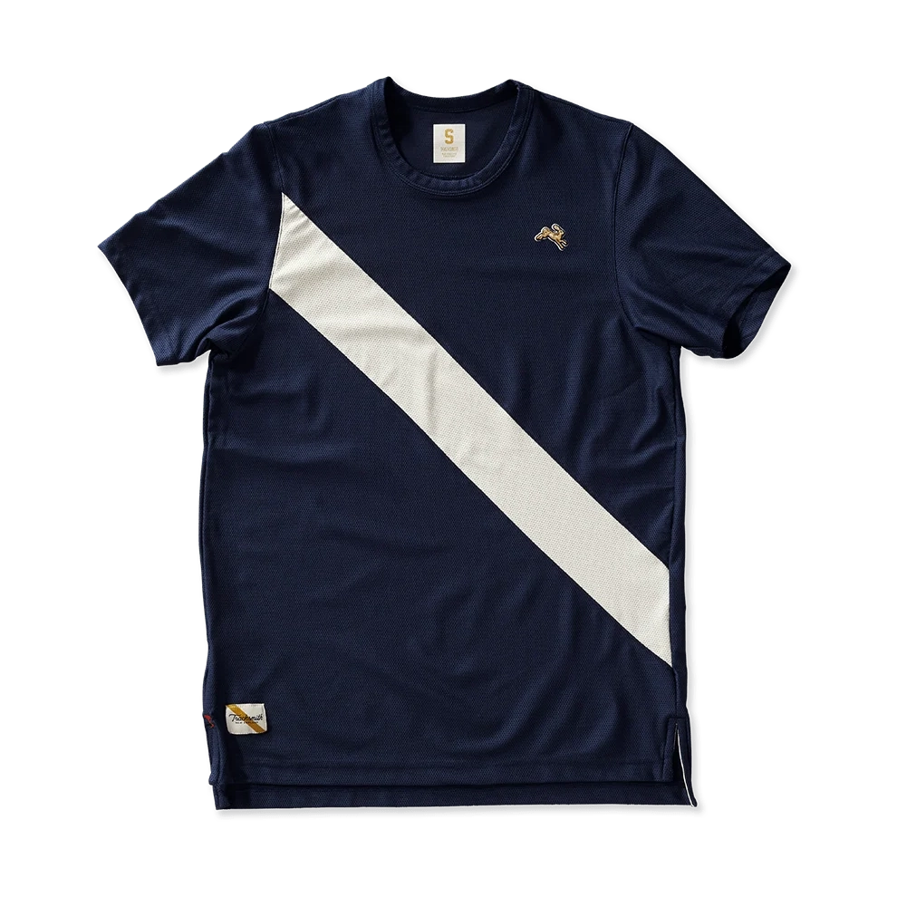 A navy blue Vancortlandt Tee – Men's athletic t-shirt with a bold diagonal white stripe across the chest, a small gold bird logo on the left chest, and a small gold-and-white patch near the bottom hem, shown against a solid green background.