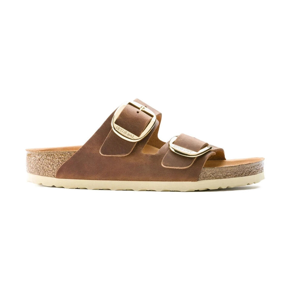 A pair of brown BIRKENSTOCK Arizona Big Buckle double-strap leather slide sandals with gold-tone buckles and a cork-textured footbed, shown from a side profile on a white background.