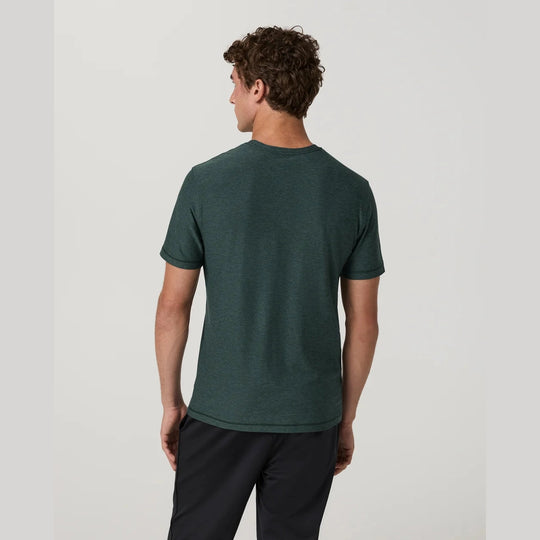 A man shown from the back wearing a dark green short-sleeve crewneck t-shirt and dark pants, photographed against a light gray studio background.