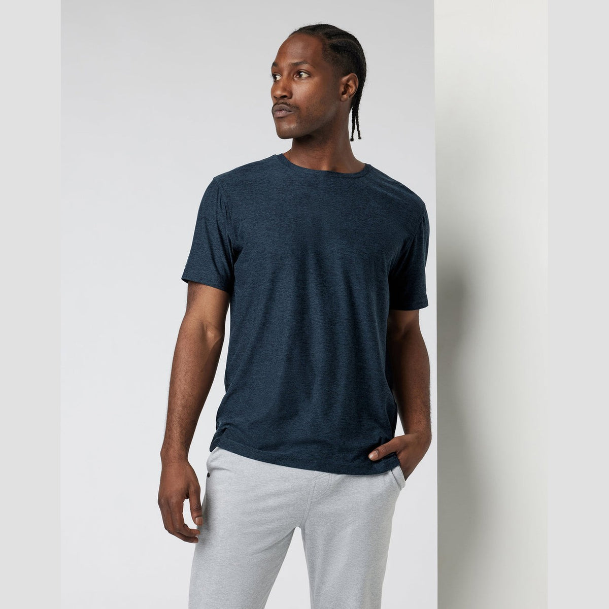 Man wearing a dark blue Strato Tech Tee – Men's t-shirt and light gray pants against a plain background