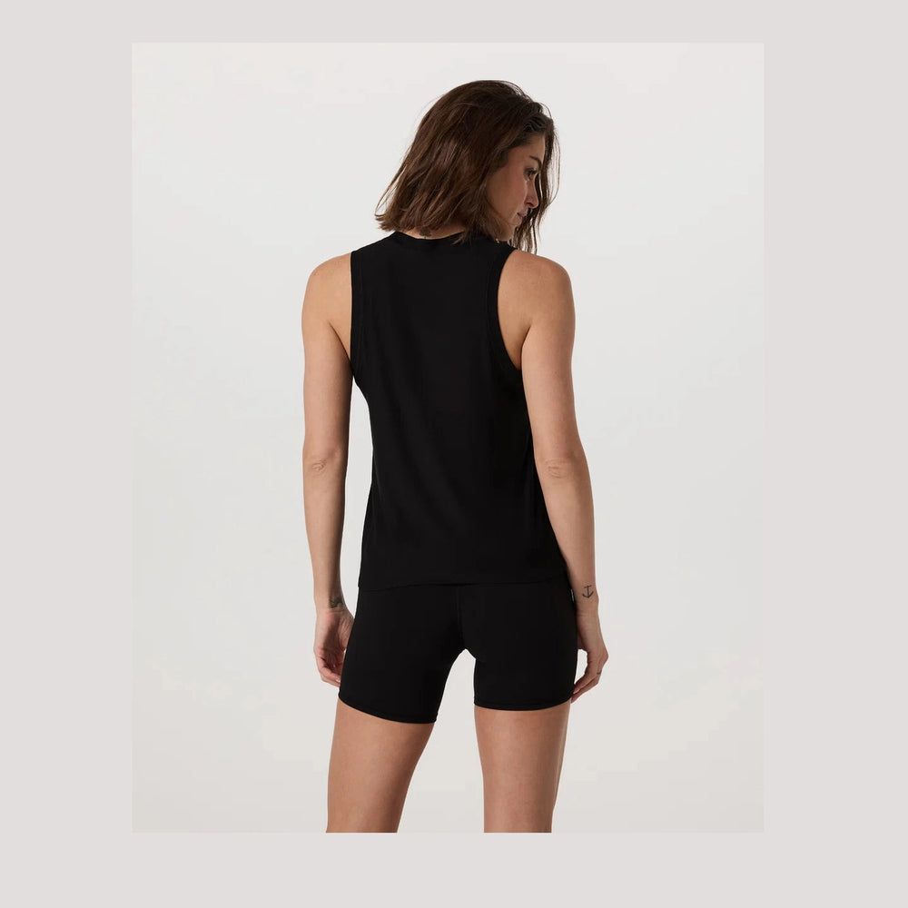 Woman wearing a black Vuori Energy Top Long – Women's sleeveless top and shorts on a white background