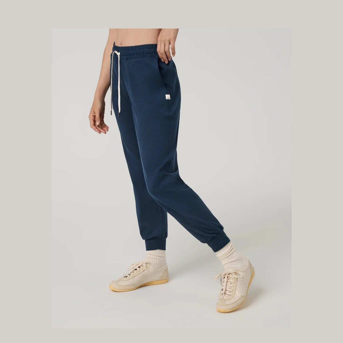 Person wearing navy blue Vuori Performance Jogger – Women's jogger pants with a white logo on a light gray background