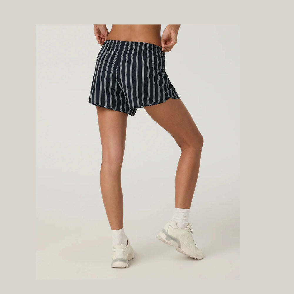Person wearing navy and white striped  Vuori Clementine 2.0 4" Shorts--Women's shorts on a plain background