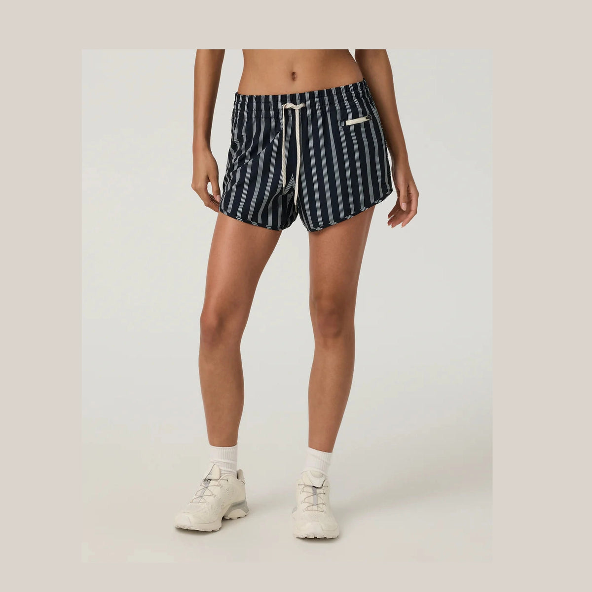 Person wearing navy and white striped Vuori Clementine 2.0 4" Shorts--Women's shorts on a plain background