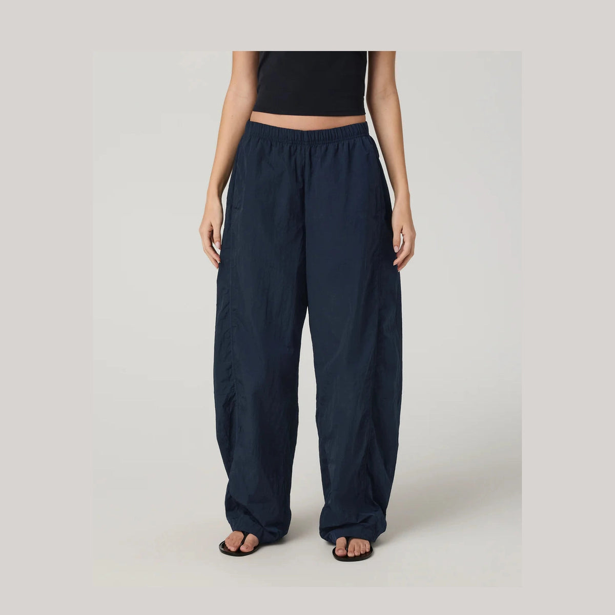 Person wearing navy blue wide-leg Retrograde Track Pant--Women's pants on a plain background