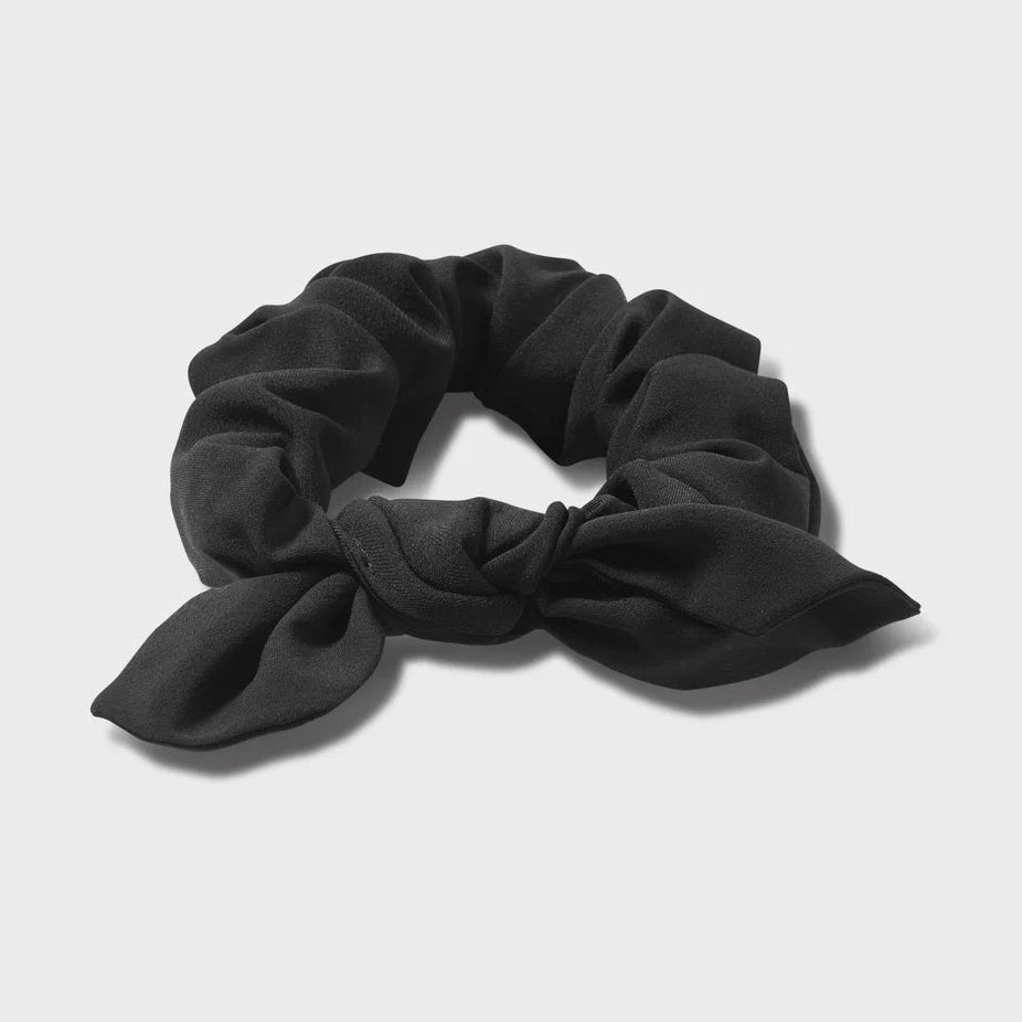 Black Vuori Tie Scrunchy with a bow on a light gray background