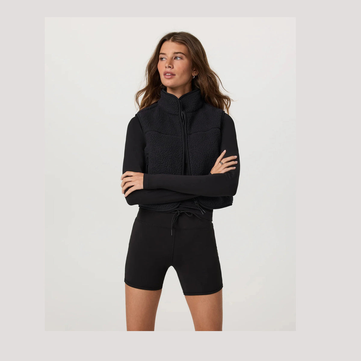 Woman wearing a black Alpine Vest--Women's with a high collar on a white background