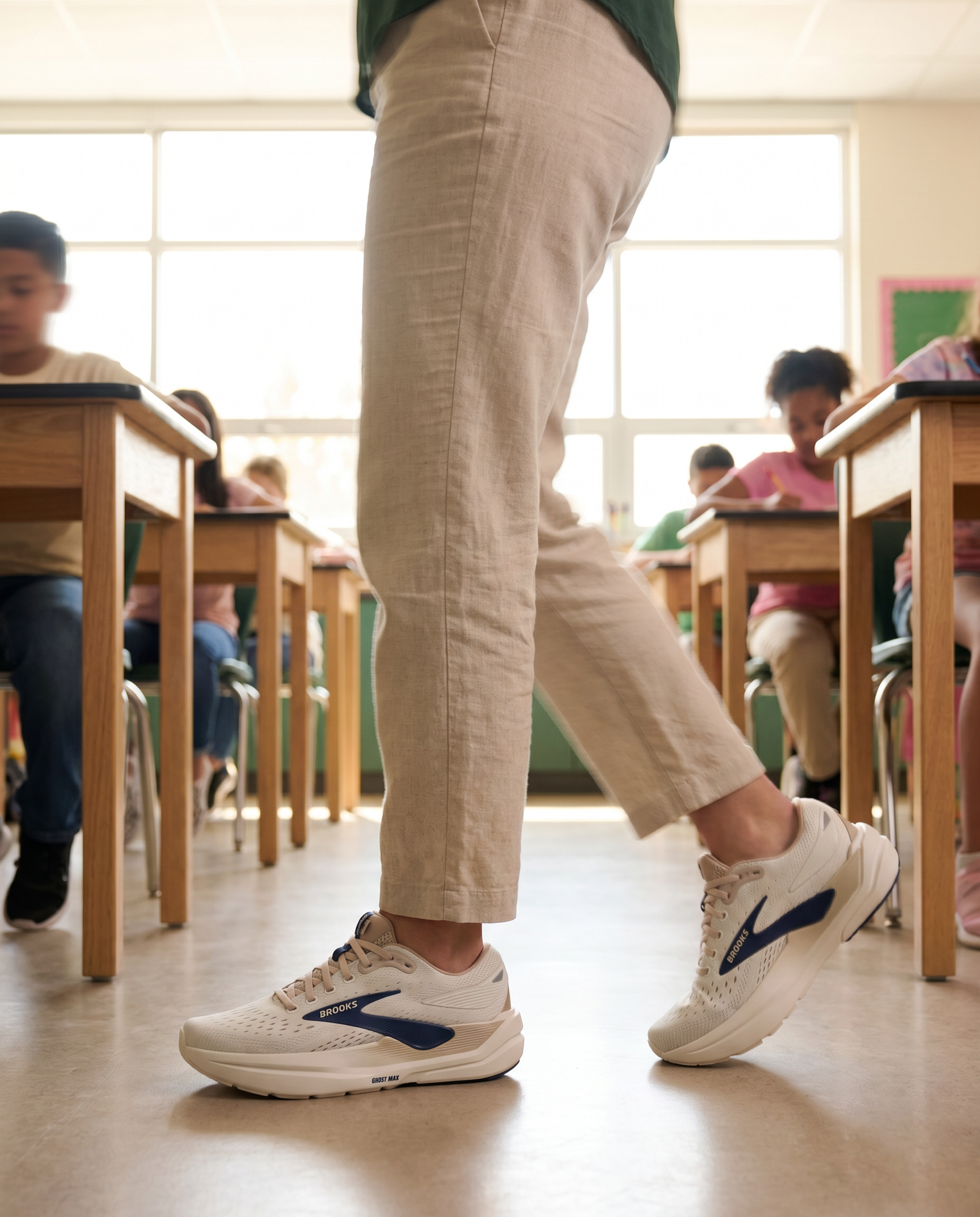 Person standing in Brooks Ghost Max 3 in a classroom with desks and students in the background